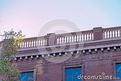 Flat roof balcony with decorative handrails in bright evening shade and sunny white sky background Stock Photo