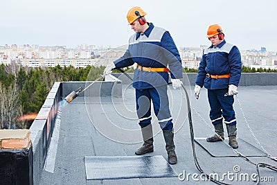 Flat roof installation. Heating and melting bitumen roofing felt Stock Photo