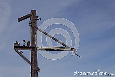 Flat steel poles with outriggers and light fixtures against blue sky, rusted metal patina Stock Photo
