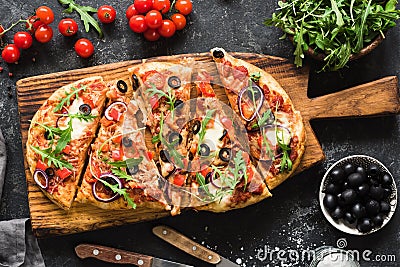 Flatbread pizza garnished with fresh arugula on wooden pizza board, top view Stock Photo