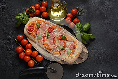 Flatbread pizza garnished with fresh cherry tomatoes, basil, cheese and olive oil on wooden pizza board. Stock Photo