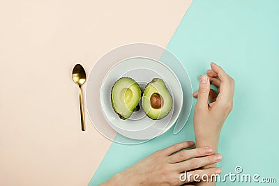 Flatlay with cut avocado on white plate and woman`s hands Stock Photo