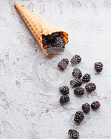 Flatlay of fresh blackberries spilling out of a waffle ice cream cone Stock Photo