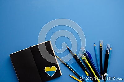 Flatlay horizontal composition black notebook pages, heart patch, black felt-tip pens with blank blue background Stock Photo