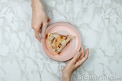 Flatlay of men passing the piece of apple pie to woman`s hand Stock Photo