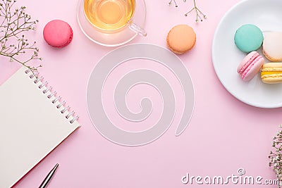 Flatlay of notebook, cake macaron, cup of tea and flower on pink Stock Photo
