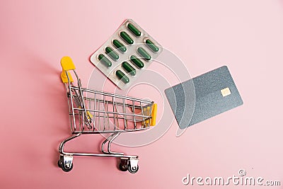 Flatlay, shopping cart, bank card and pills in a blister on a pink background Stock Photo
