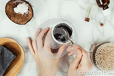 Flatlay of woman`s hands preparing homemade charcoal soap with the ingredients on the side Stock Photo
