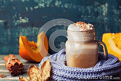 Flavored pumpkin spiced latte or coffee in cup decorated knitted scarf on teal vintage background. Autumn, fall, winter hot drink. Stock Photo