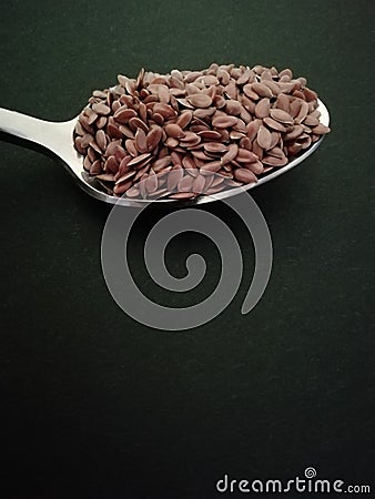 Flax seeds in the spoon on black background, vintage color tone. Copy space Stock Photo