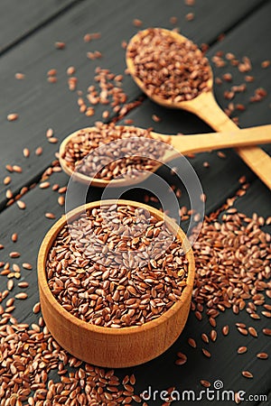 Flax seeds on wooden bowl and spoon on black background Stock Photo