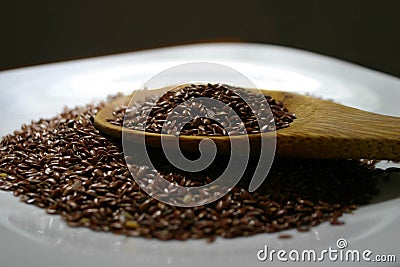 Flaxseeds spoon. Wooden spoon of flaxseeds on the white plate. Stock Photo