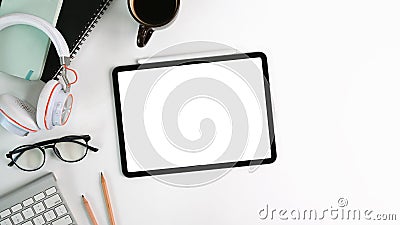 Top view white office desk with digital talet with empty screen , headphone, glasses, coffee cup and notebook. Stock Photo