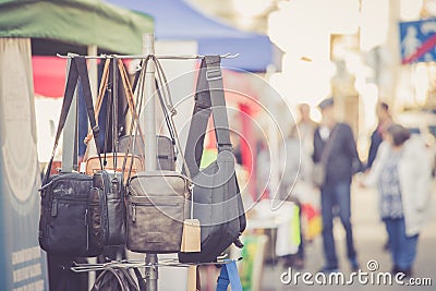 Flea market: bags, purse and handbags in the foreground, people in the blurry background Stock Photo