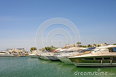 Fleet of large white boats are moored in a serene coastal bay, the sun glinting off their hulls Stock Photo
