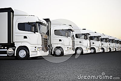 Fleet of white commercial transportation trucks parked in a row ready for business distribution . Stock Photo