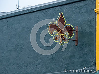 Fleur-de-lis neon symbol hanging outside of building against blue wall Editorial Stock Photo
