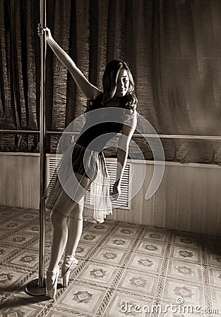 Flexible ballet dancer stretching in retro style. Ballerina dances near pole Stock Photo