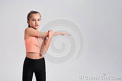 I play fitness. Flexible cute little girl child looking at camera while doing exercise isolated on a white background Stock Photo