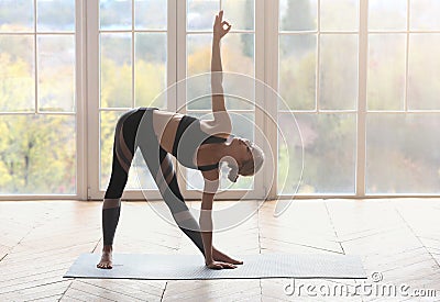 Flexible girl making triangle yoga pose at fitness studio Stock Photo