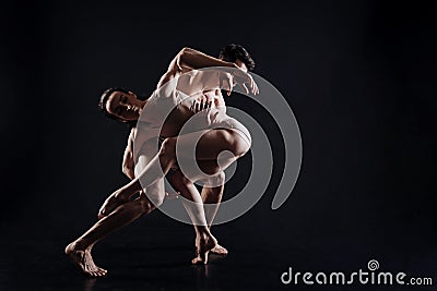 Flexible gymnasts performing in the black colored studio Stock Photo