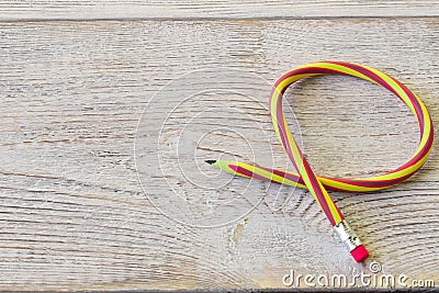 Flexible pencil on old wooden table . Bending pencil Stock Photo