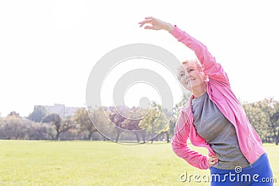 Flexible senior woman exercising on sunny day in park Stock Photo