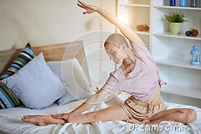 Flexible short-haired woman on white bed practicing yoga Stock Photo