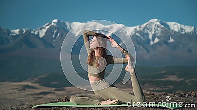 Flexible sportive young woman practices yoga on background of snow-capped mountains Stock Photo