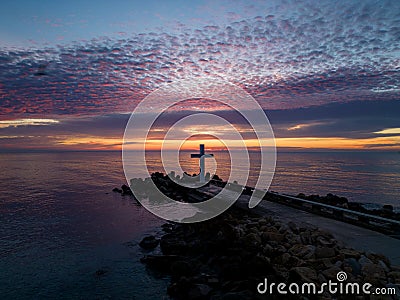 A flight around a Christian Holy cross early in the morning at sunrise. The large cross stands on the edge of a Stock Photo