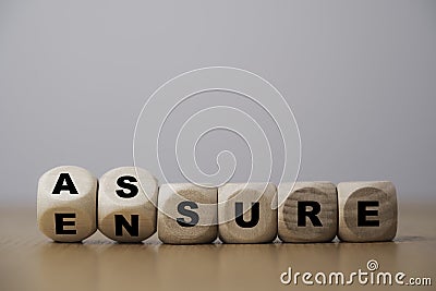 Flipping wooden cube block for change between Assure and Ensure for Insurance and assurance concept Stock Photo