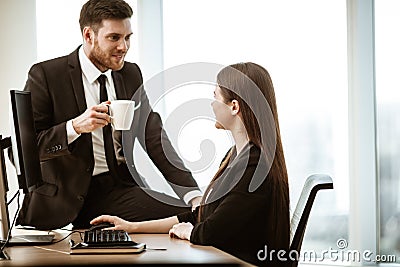 Flirt and relations at work. Smiling male businessman sits and shows sexual interest to positive minded female assistant Stock Photo