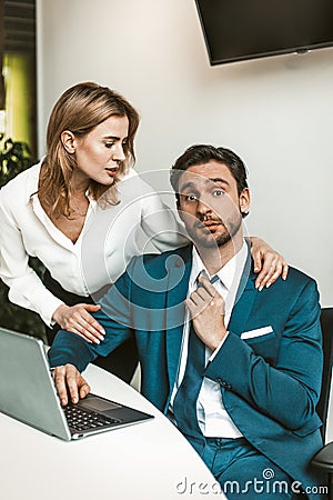Flirtation or sexual harassment. Blonde woman seduces man working with laptop, colleagues flirt at work. Seducing a Stock Photo