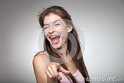 Flirtatious girl pointing on camera and winking. Stock Photo