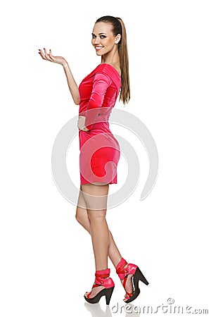 Flirtatious young woman in pink dress showing blank copy space Stock Photo