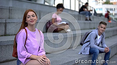 Flirting beautiful teen female sitting near student smiling to girl, sympathy Stock Photo