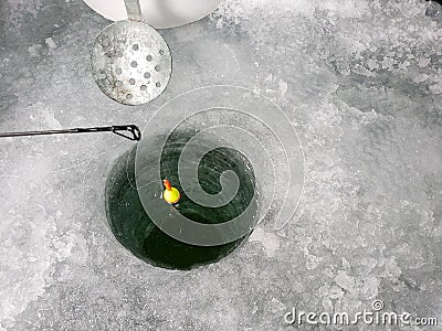 A float sits in a an ice fishing hole. Stock Photo