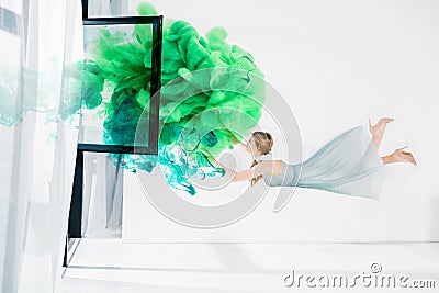 Floating girl touching green and turquoise clouds Stock Photo