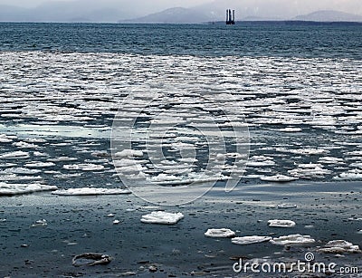 Floating ice with oil rig in the background Stock Photo