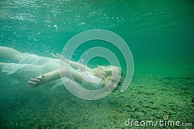 A floating woman. Underwater portrait. Girl in white dress swimming in the lake. Green marine plants, water Stock Photo