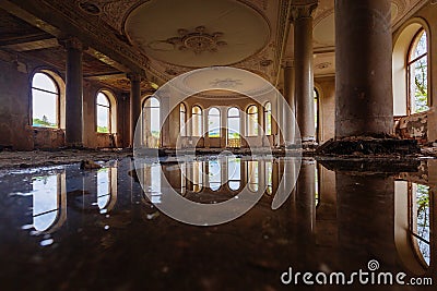 Flooded large hall with columns in old abandoned mansion, water reflection Stock Photo