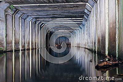 Flooded sewer tunnel is reflecting in water. Dirty urban sewage flowing throw rectangular sewer tunnel Stock Photo