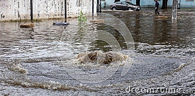 Flooding after heavy rains in city. Sewage broke open asphalt and blew up fountain. Dirty sewage broke through storm sewer and Editorial Stock Photo