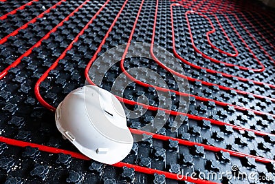 Floor heating installation, pipes and pipelines. White engineer helmet Stock Photo