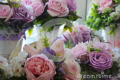 Floral arrangement of pink and lilac peonies and roses with green leaves in white vases. Beautiful floral background Stock Photo