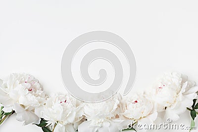 Floral border of white peony flowers on pastel table top view. Flat lay style Stock Photo