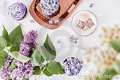 Floral feminine background. Purple cupcakes using trend Dreamy Escapism. Desserts on the golden tray, coffee cup and Stock Photo