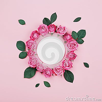 Floral frame made of white blank, pink rose flowers and green leaves on pastel background top view. Flat lay styling. Stock Photo
