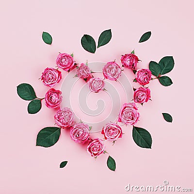 Floral heart made of pink rose flowers and green leaves on pastel background top view. Flat lay styling. Fashion composition. Stock Photo