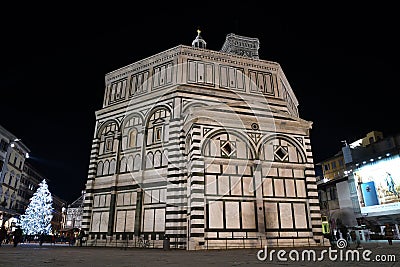 Florence, December 2018: Illuminated Christmas tree in Piazza del Duomo in Florence. Baptistery on Foreground. Editorial Stock Photo